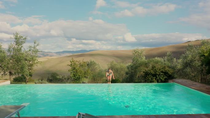 托斯卡纳地区，一名空中女子跳进她田园诗般的度假别墅的游泳池