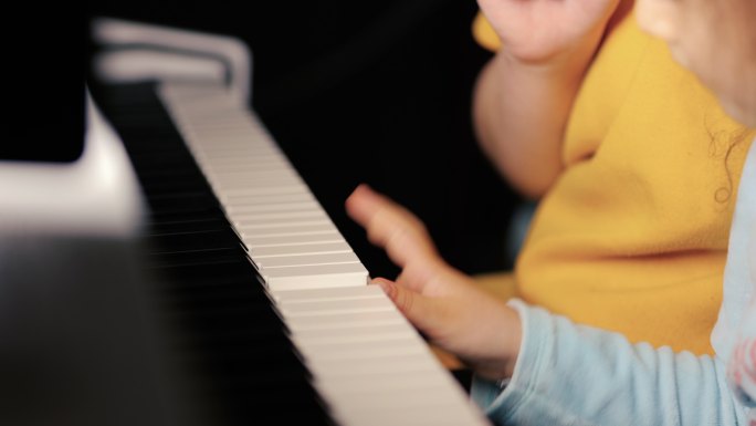 小卷发女孩弹钢琴，女孩在电影灯光下弹钢琴，戏剧性的灯光，特写手指弹钢琴，情绪化的演奏，可爱的小女孩弹