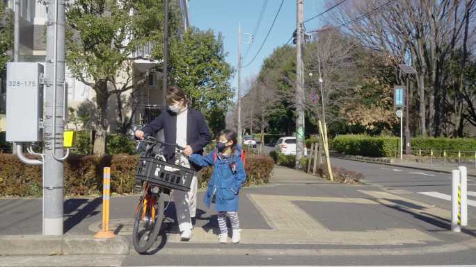 早上，母亲和小学生一起走在街上。母亲去上班女儿去上学