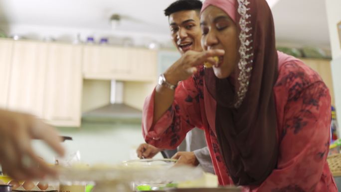马来西亚马来族母亲和儿子女儿在厨房品尝自制饼干