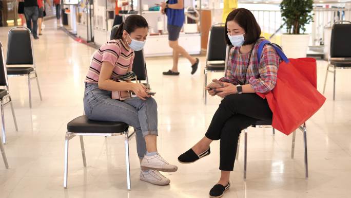 泰国曼谷，一名亚裔女子坐在社交场所一边使用手机。