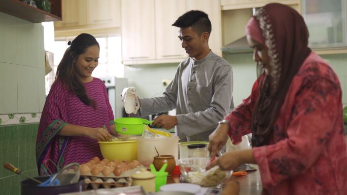 马来西亚马来同胞成年子女在厨房帮助母亲烤面包，在家为家人庆祝哈里·拉亚节做准备