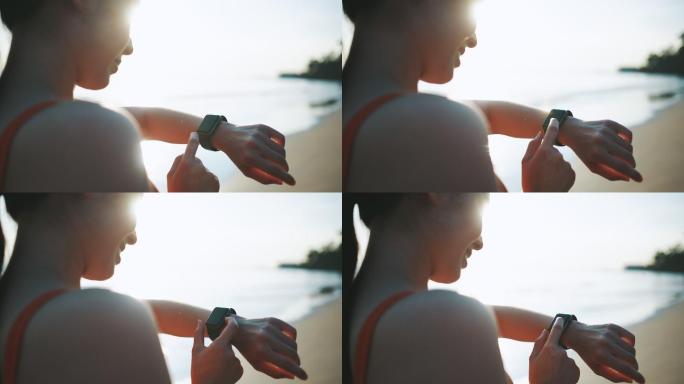 亚洲运动女性使用智能手表监控自己在沙滩上的跑步表现