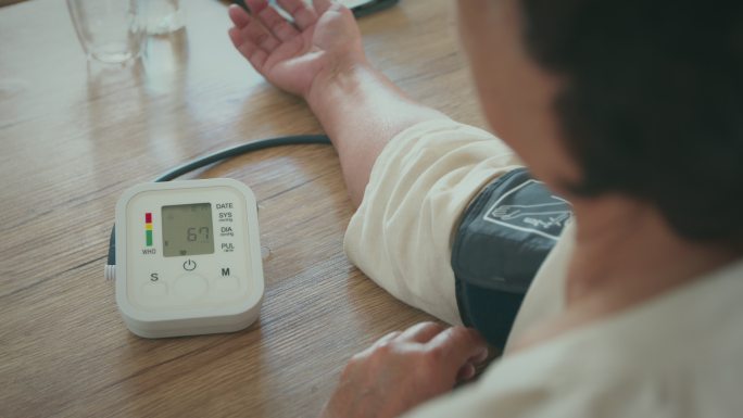 这位年长的女士正在家里用数字血压计检查血压和心率。