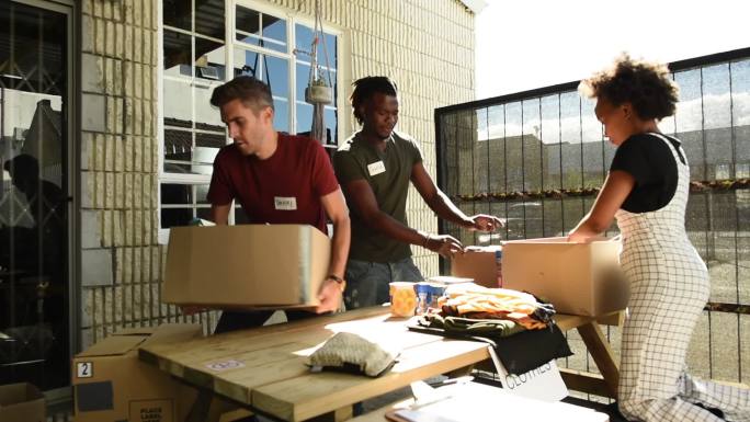 年轻志愿者分拣捐赠食品和衣物的箱子