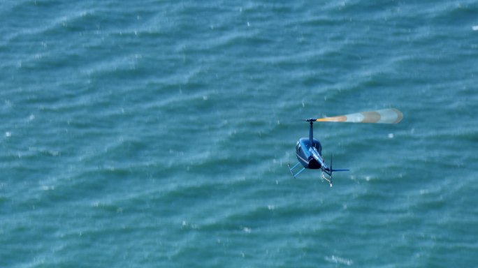 在阳光明媚的日子里，一架直升机在海上飞行