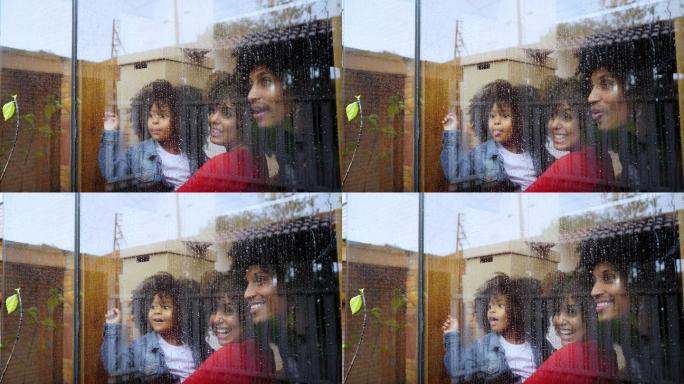 一位非洲裔拉丁裔的母亲、父亲和女儿在下雨时寻找他们新房子的窗户。这种情况发生在新冠肺炎19年期间