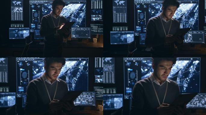 在一间黑暗的办公室里，一个穿着毛衣的男人独自在一台数字平板电脑上工作