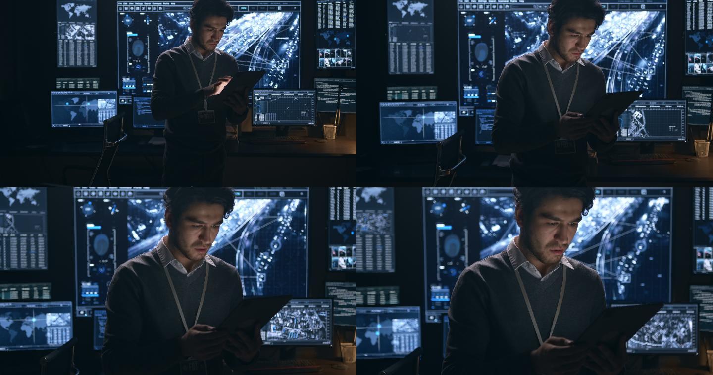 在一间黑暗的办公室里，一个穿着毛衣的男人独自在一台数字平板电脑上工作