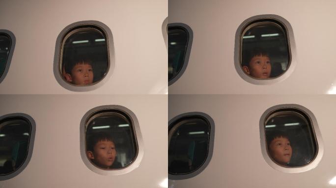 一个男孩坐在商用飞机旁的窗户上。他坐在那里望着窗外的景色。带着能坐飞机旅行的兴奋。