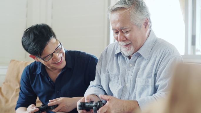 年长的父亲和他成年的儿子喜欢一起玩电子游戏。