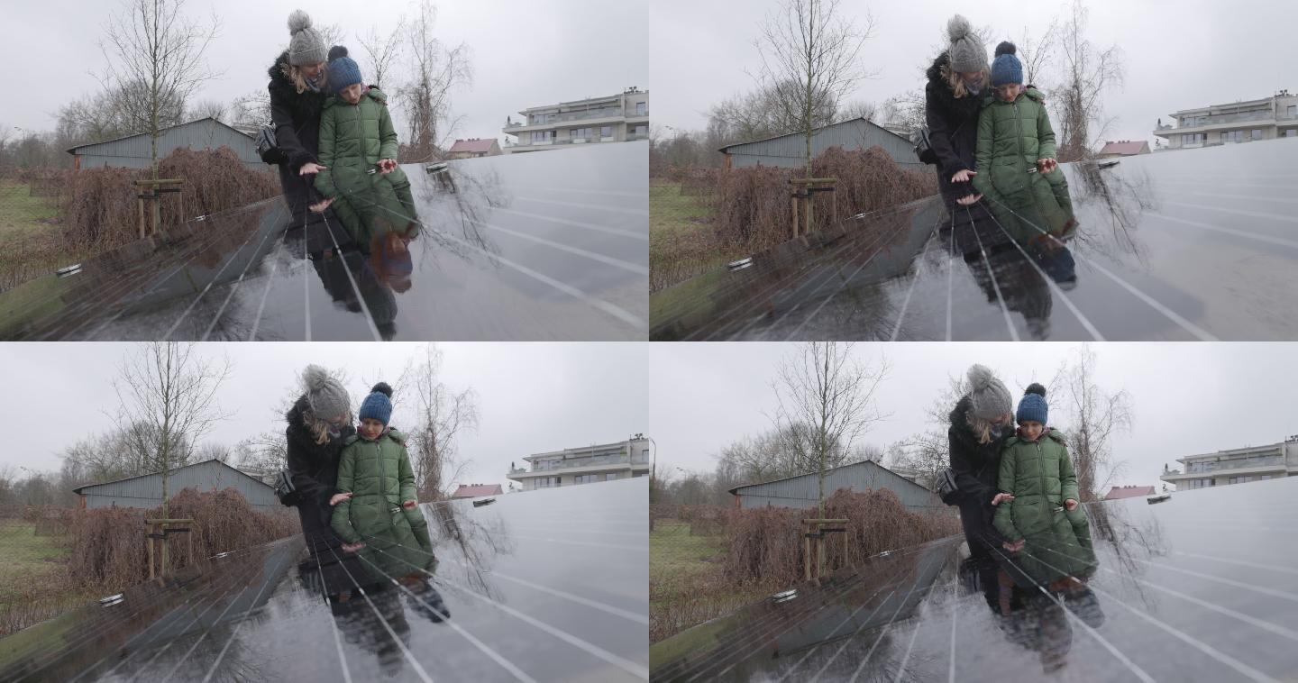 母亲在雨天向儿子解释太阳能电池板技术。