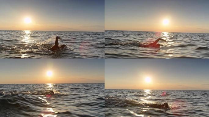TS男子公开水域游泳运动员日落时在波涛汹涌的大海中游泳
