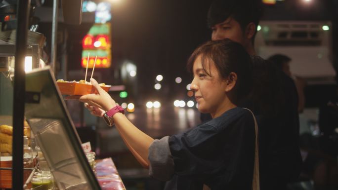 一对亚洲情侣在街头美食上约会。