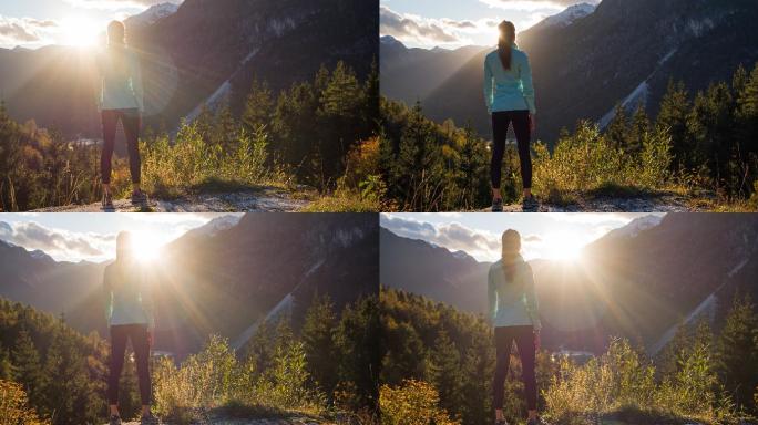 年轻的女性徒步旅行者在日落时从悬崖边欣赏山谷湖的壮丽景色