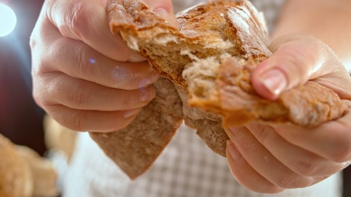 女人的手把面包撕成两半