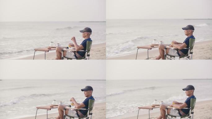 老人在海滩上放松时喝橙汁。