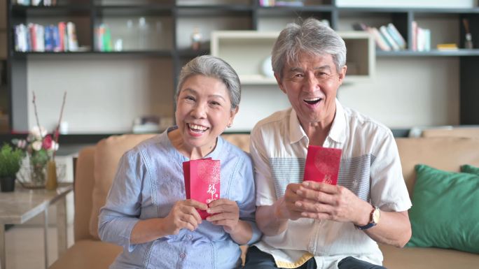 中国新年老人夫妇祖父母在客厅里拿着红包看着相机