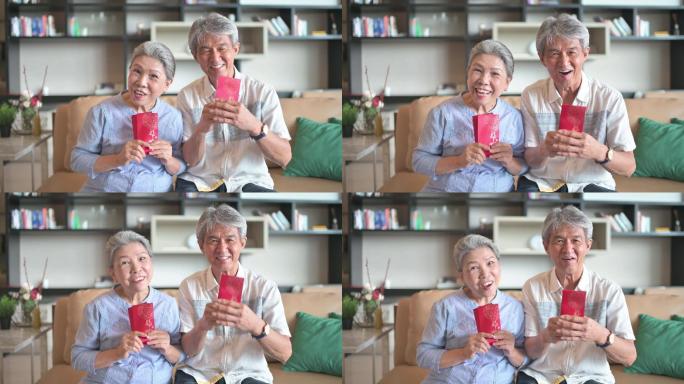 中国新年老人夫妇祖父母在客厅里拿着红包看着相机