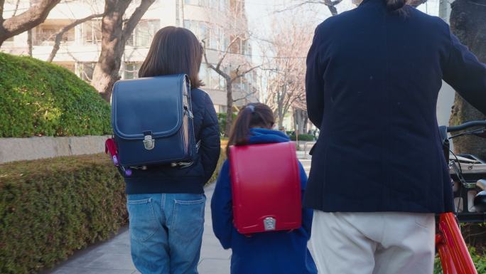 母亲和女儿们走在街上。母亲去上班，女儿去上学