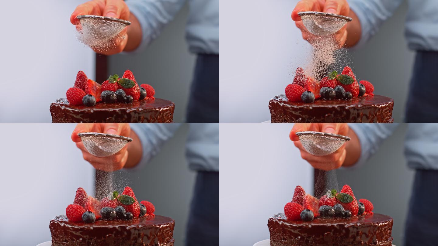 一位男厨师用手在巧克力蛋糕上撒砂糖