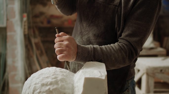 男雕塑家的斯洛·莫（SLO MO）手在雕刻雕塑