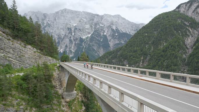 由五名公路自行车手组成的空中骑行队，他们骑在高山上的一座桥上