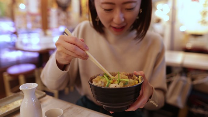 一名年轻的日本女子在Izakaya酒吧吃“东布里”鸡肉日本料理