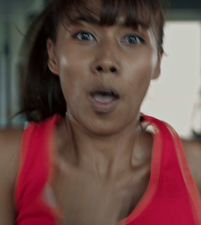 女性在跑步机上快速奔跑的垂直视频。