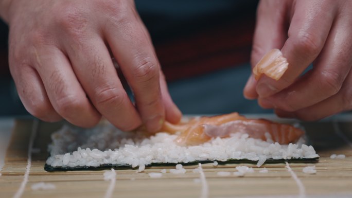 日本厨师在做寿司卷时把三文鱼放在米饭上