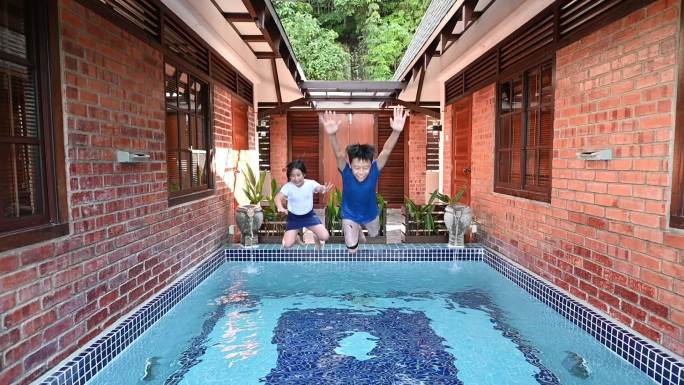 sslow motion亚裔中国年轻兄弟姐妹周末在家享受游泳池的乐趣