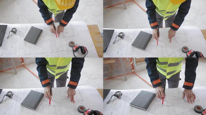 建筑工人在建筑平面图上测量距离的俯视图