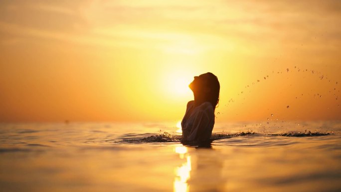 日落时在海里抛湿头发的女人