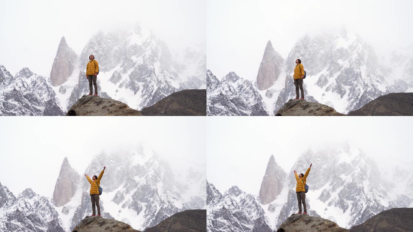 巴基斯坦北部白雪皑皑的布布利莫廷峰背景下，一名女子站在岩石上