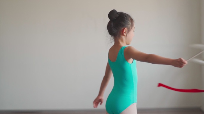 慢动作亚裔中国小女孩在体操学校用彩带练习艺术体操。芭蕾舞学校。