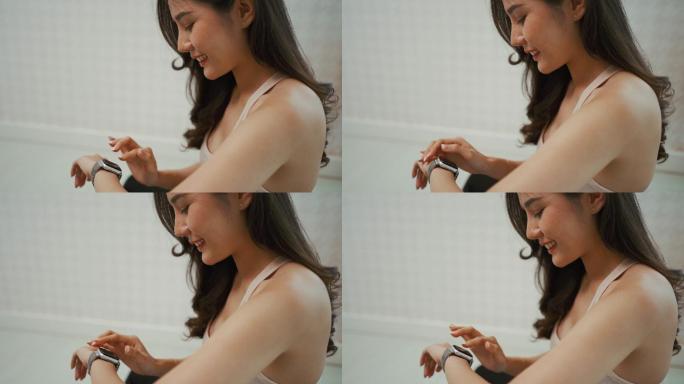亚洲女性在家锻炼后使用智能手表测量心率。