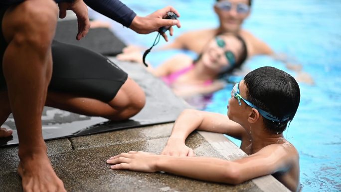 慢动作亚裔中国游泳教练在一个十几岁的男孩家中游泳后向他展示了创纪录的秒表