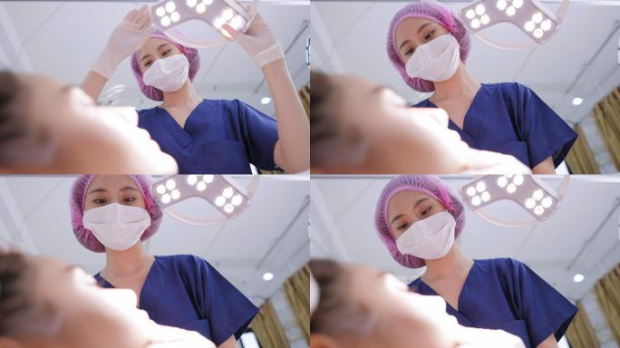 从客户人脸的低角度观察，一名女医生戴着卫生手套，戴着手术灯下的护发帽，在注射肉毒杆菌前检查面部皮肤，