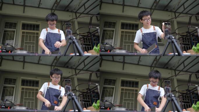 在后院厨房教烹饪广播的亚裔中国少年。