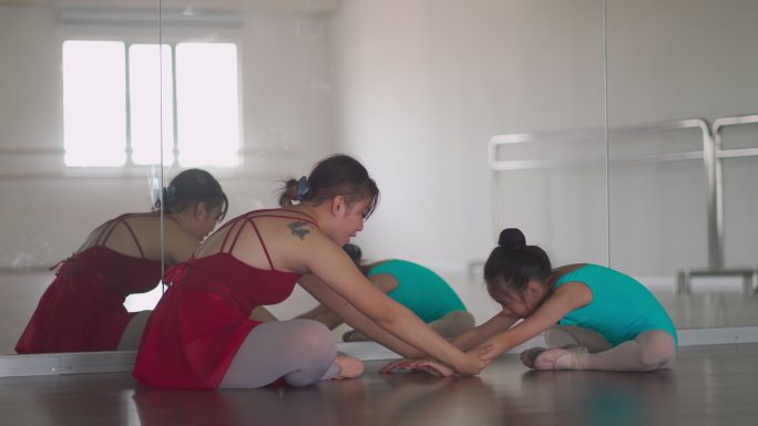 亚裔中国少女芭蕾舞演员在工作室里训练她的年轻女学生做热身运动