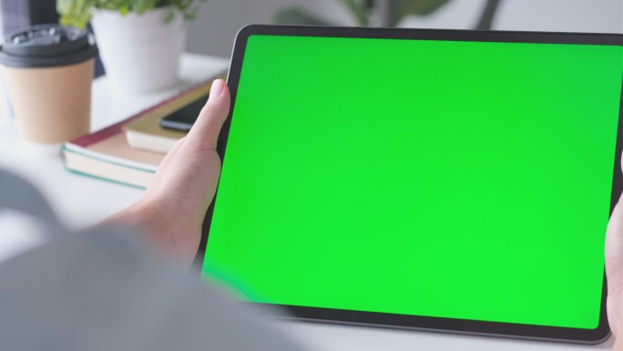站在工作台上手持绿色屏幕的数字平板电脑模型的特写镜头