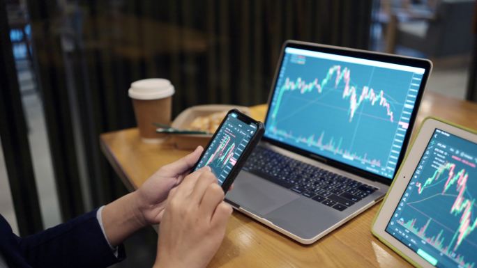 投资者正在交易股票。在电子市场上通过电脑通过手机上网。