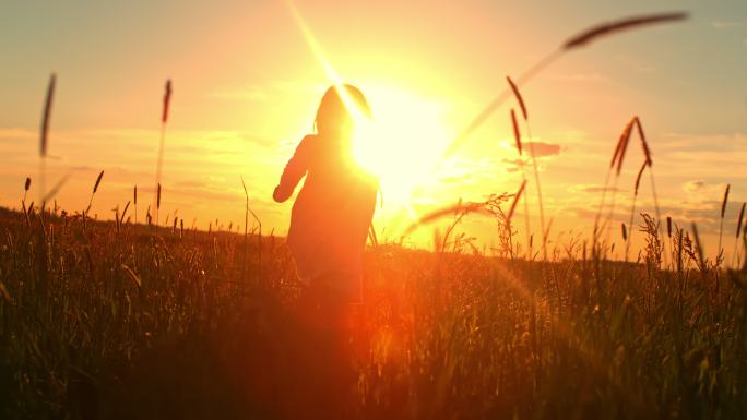 日落时分，一个小女孩在草地中央奔跑的斯洛-莫剪影