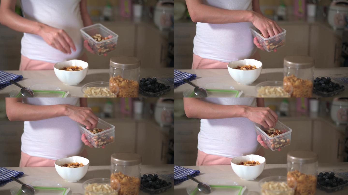 孕妇在家里做早餐玉米片麦片，并在厨房添加配料。制作富含纤维和营养的健康有机餐