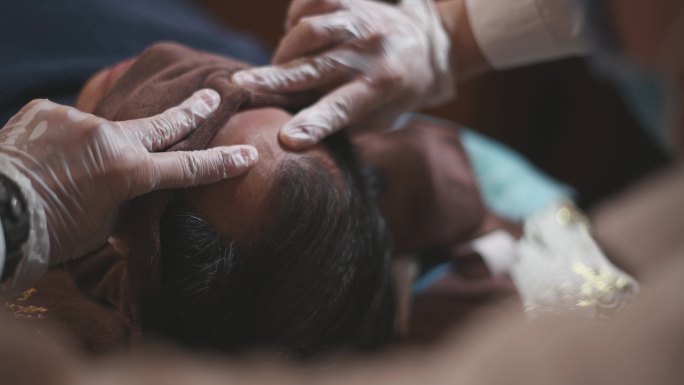 亚洲男性按摩治疗师按压患者头部穴位缓解压力指压