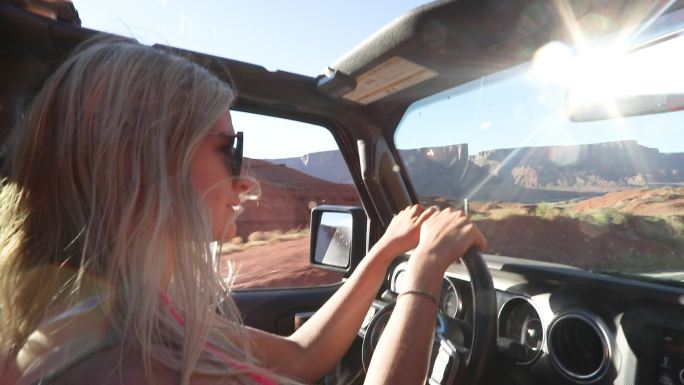 年轻女子在沙漠路上开车