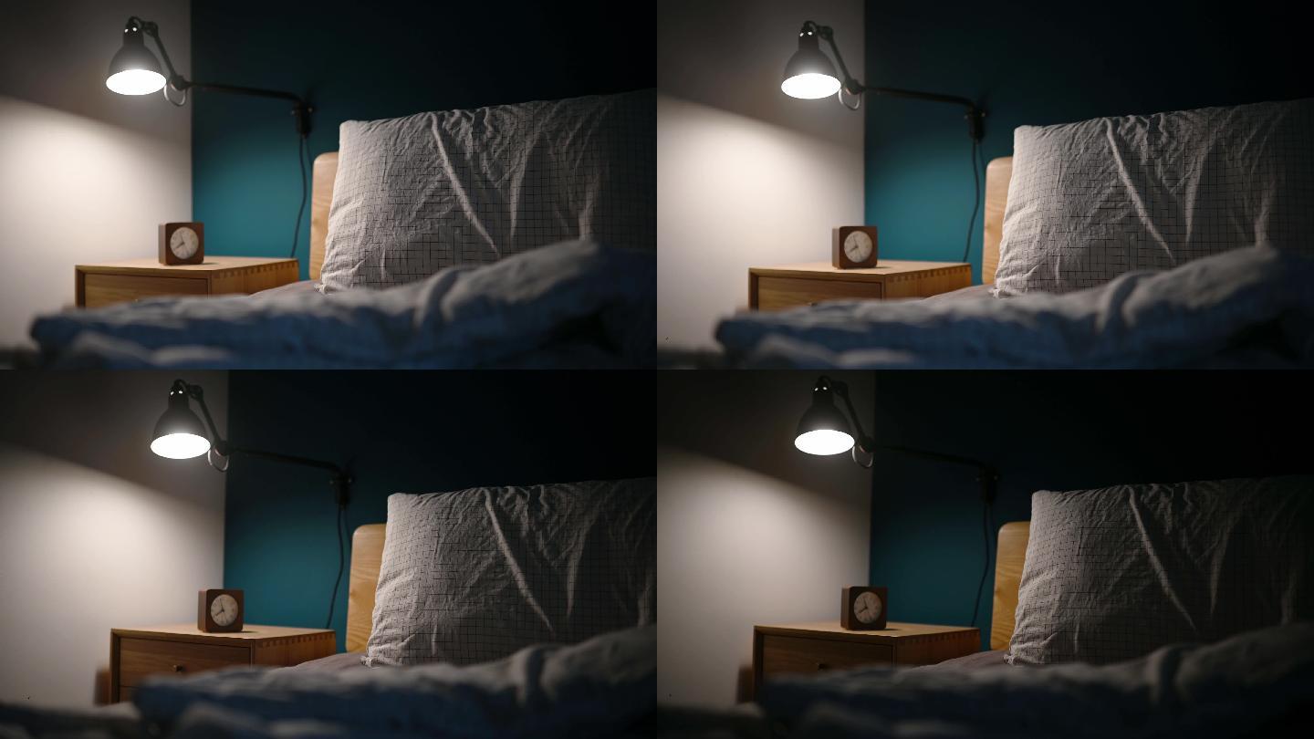夜间卧室由电灯照明，床头柜上有时钟，床边有蓝色的墙壁