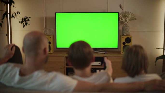 大流行期间的屏幕时间。父亲和儿子在看电视。屏幕上的色度键