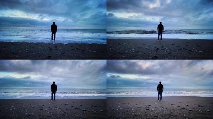 黄昏时站在海边的一个面目全非的男人。