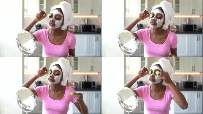 4K视频美丽的年轻非裔美国女性，脸上戴着奶油面膜，眼睛上贴着黄瓜片
